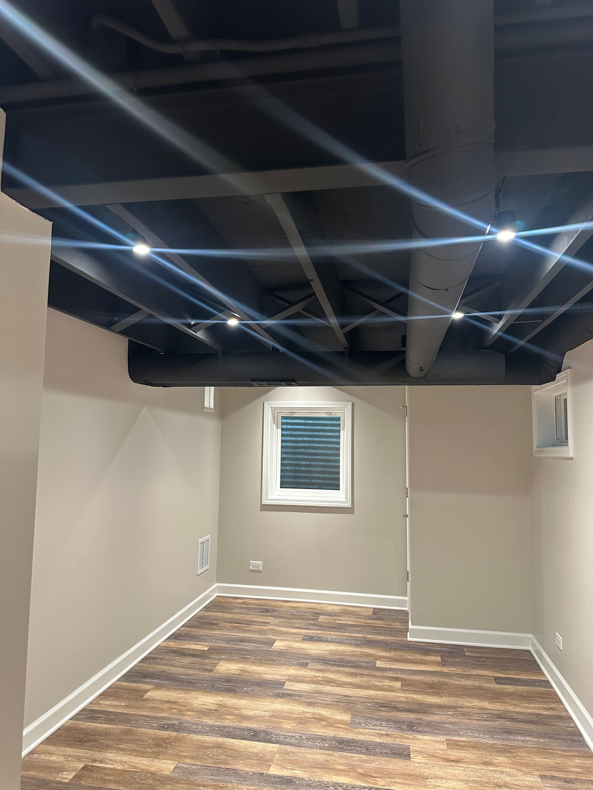 A basement with a wooden floor and a window.
