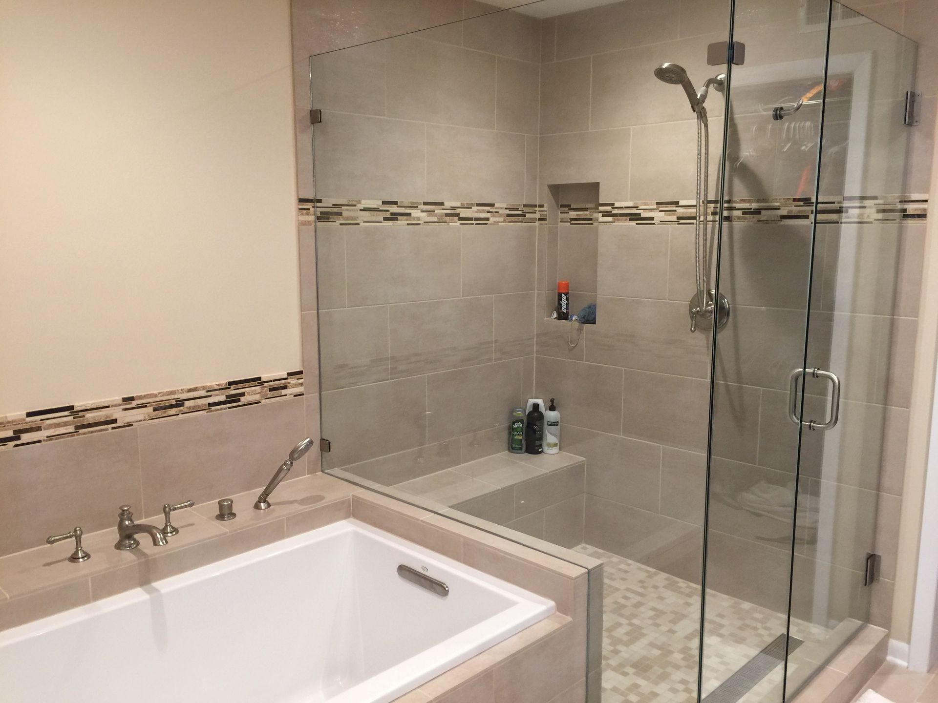 A bathroom with a bathtub and a walk in shower with a glass door.