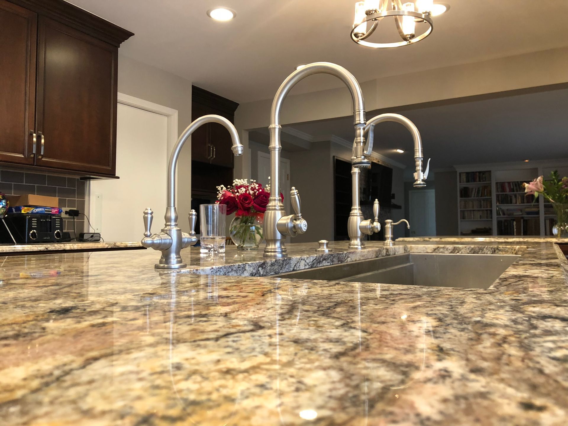 A kitchen with a sink and faucets on a granite counter top.