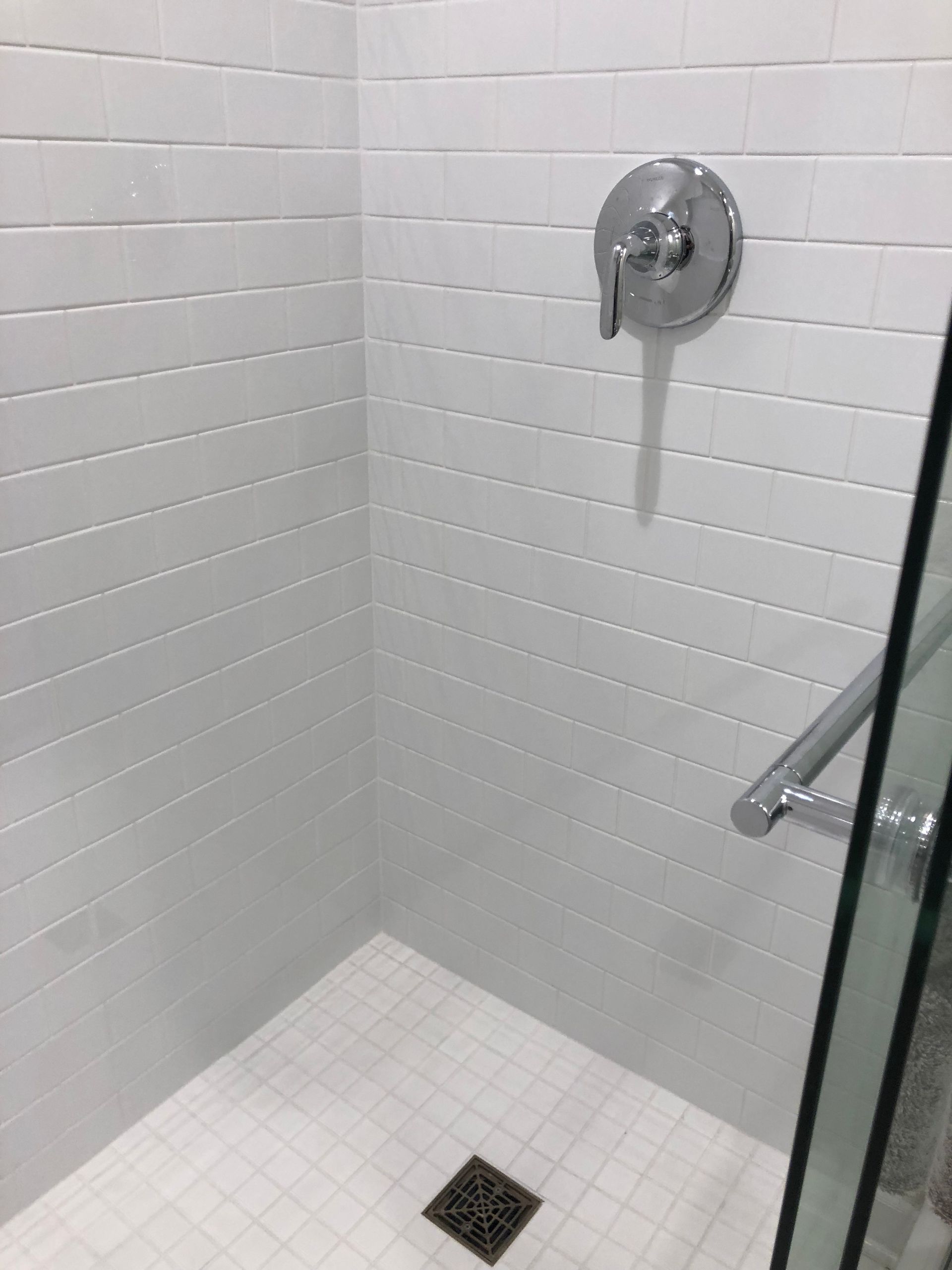 A shower stall with white tiles and a glass door.