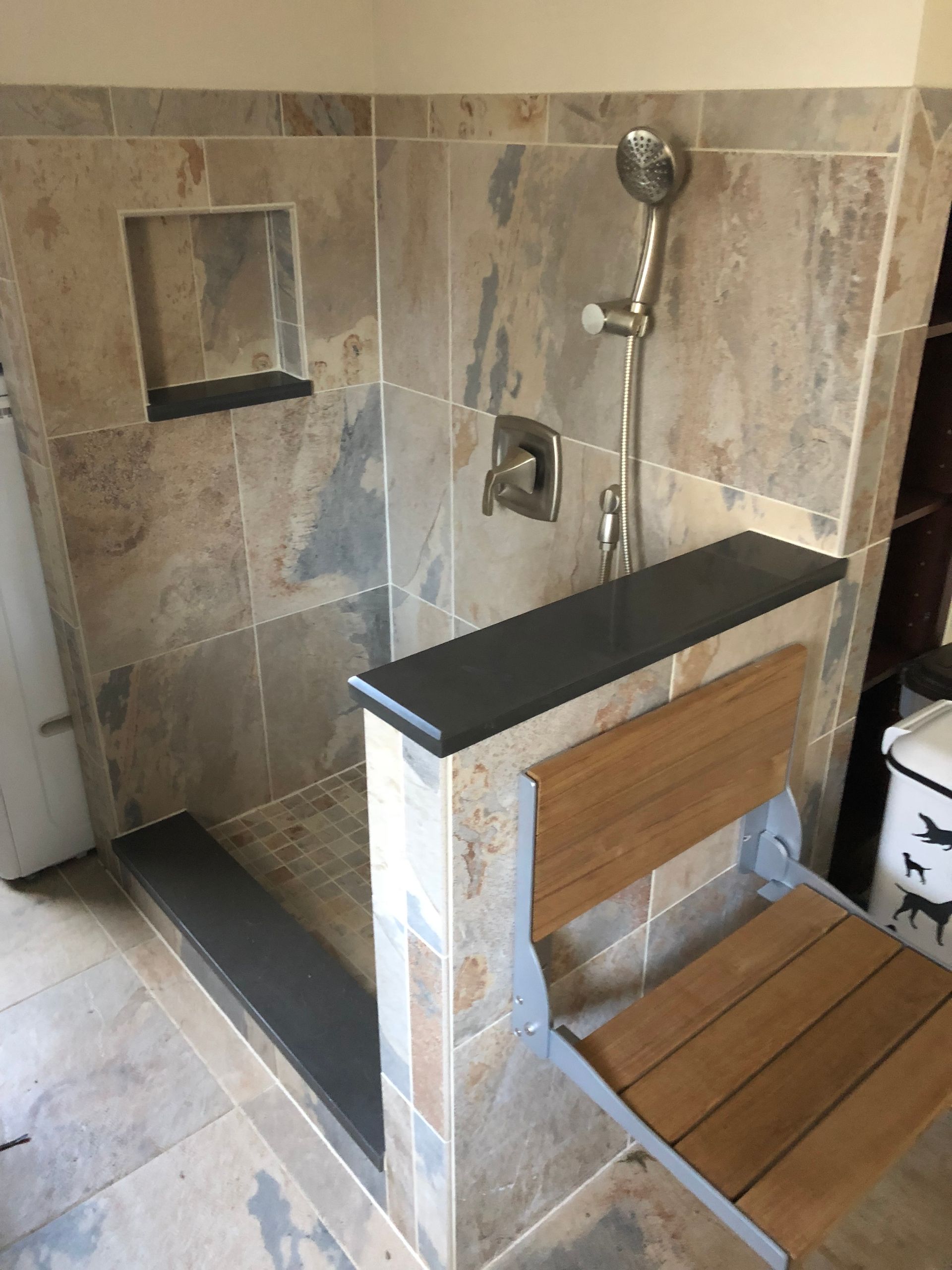 A bathroom with a walk in shower and a wooden bench.