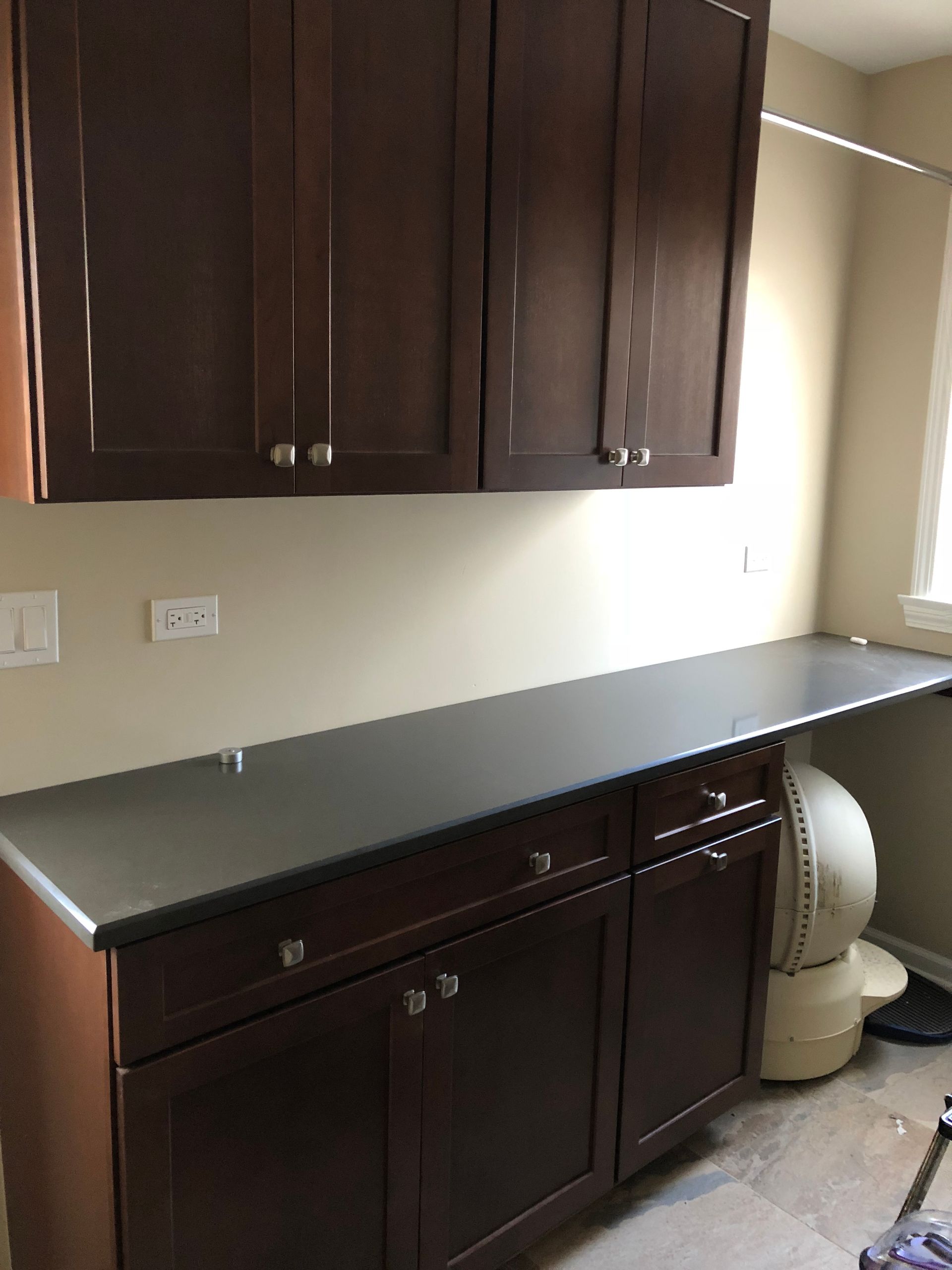 A laundry room with wooden cabinets and a black counter top