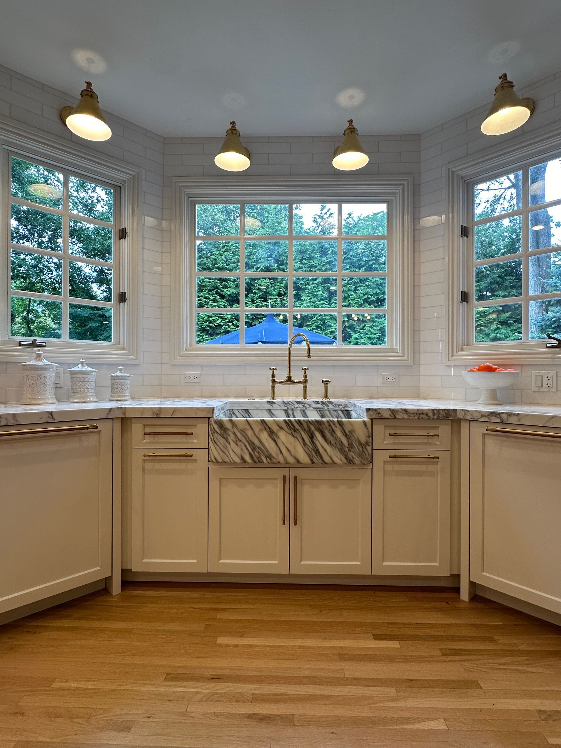 A kitchen with white cabinets , a sink , and a window.