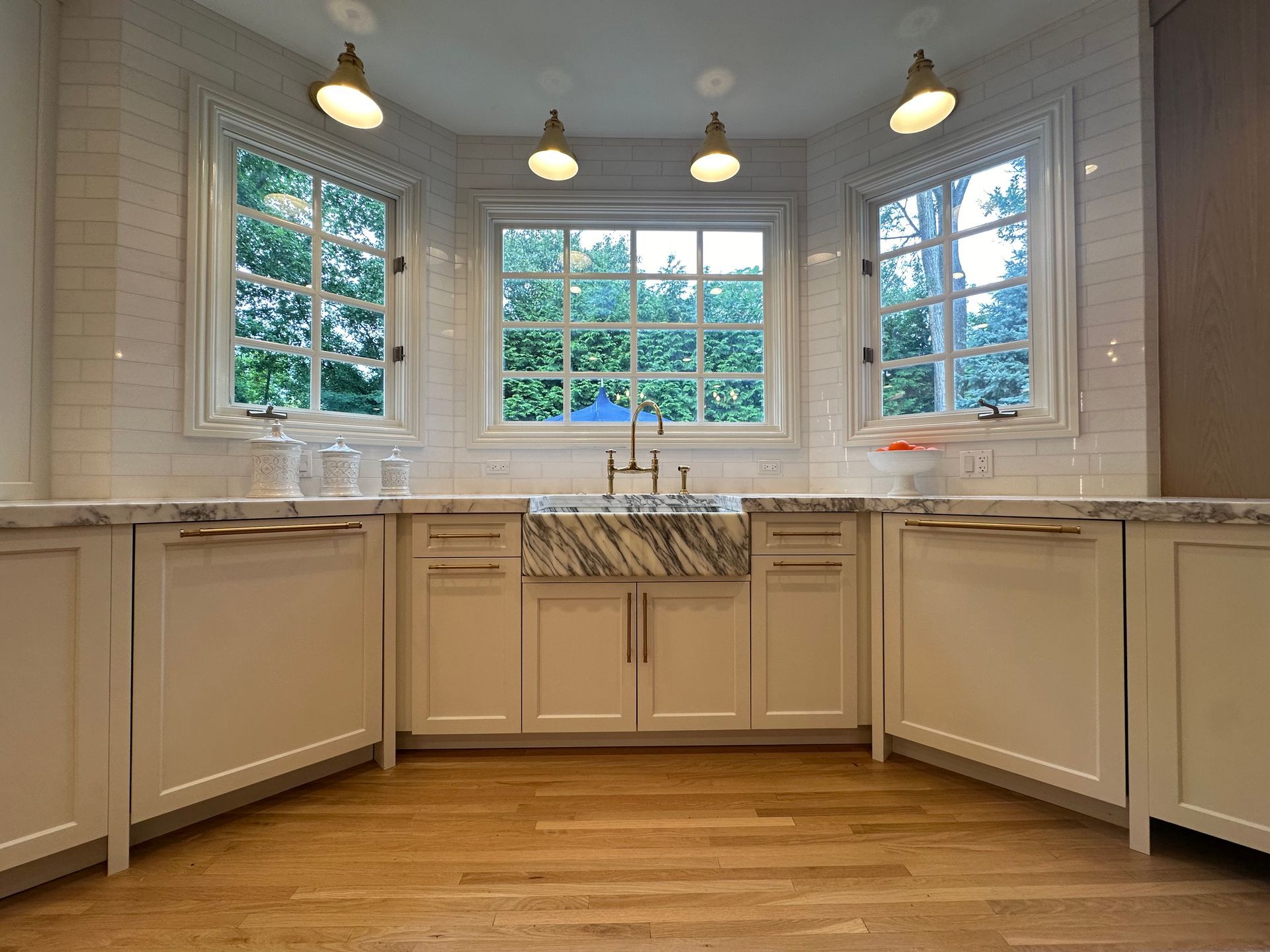 A kitchen with white cabinets , marble counter tops , and a sink.
