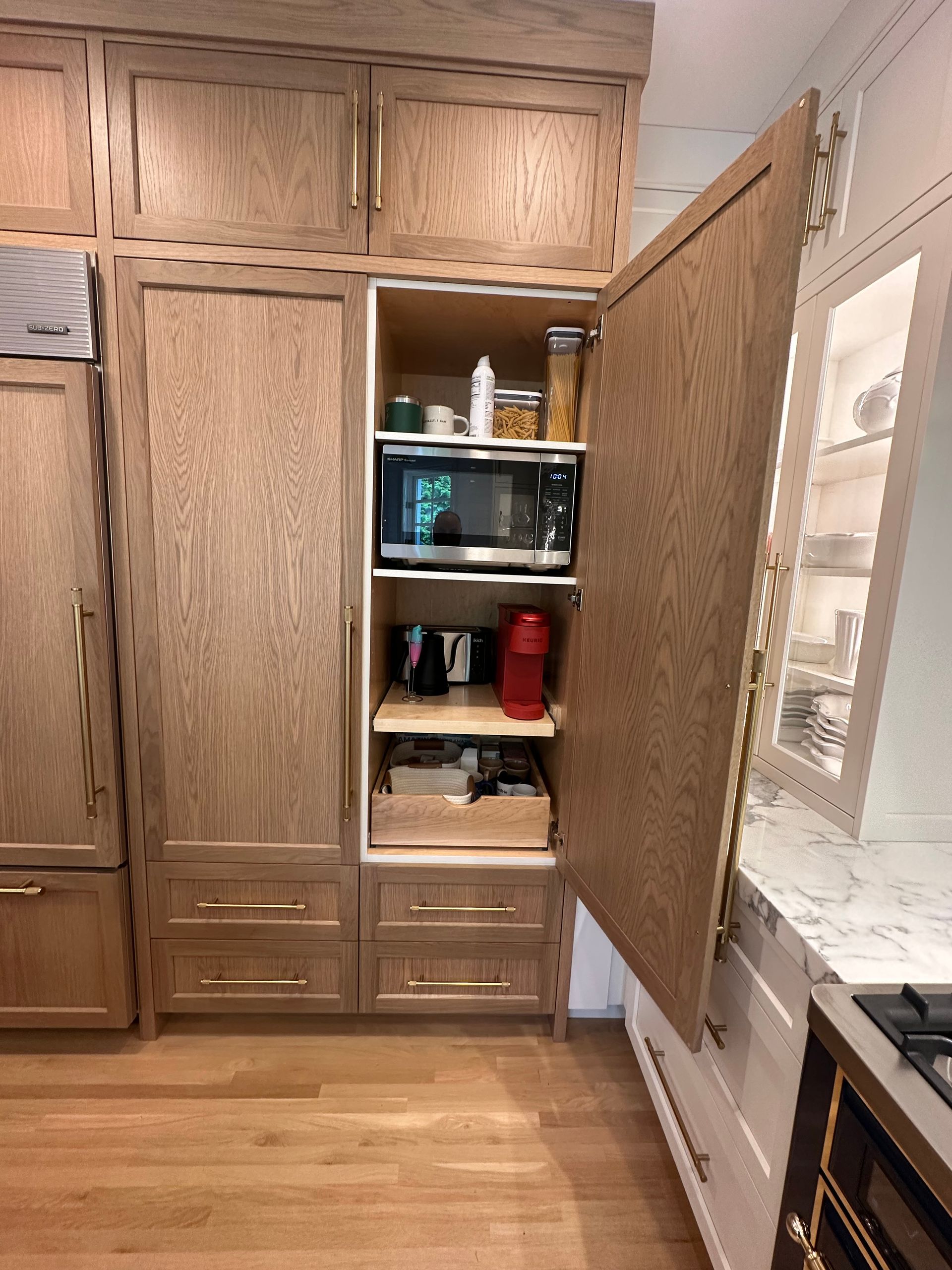 A kitchen with wooden cabinets and drawers and a microwave.