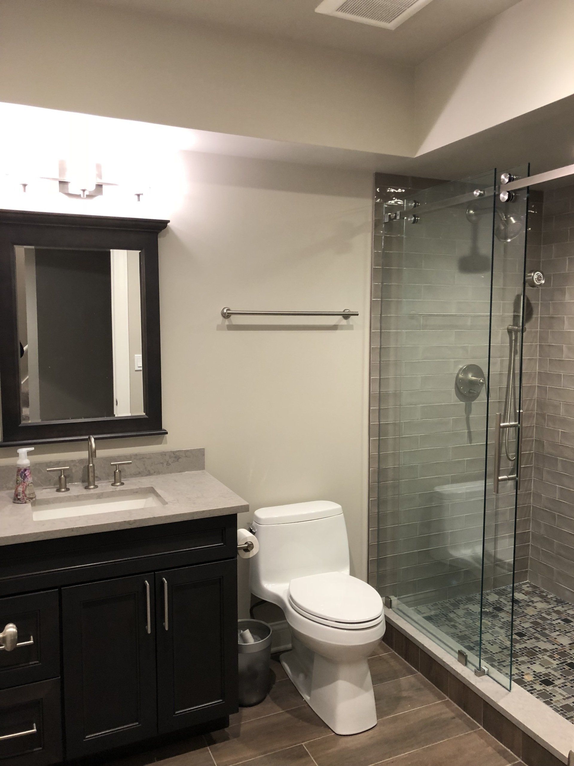 A bathroom with a toilet , sink , mirror and shower.