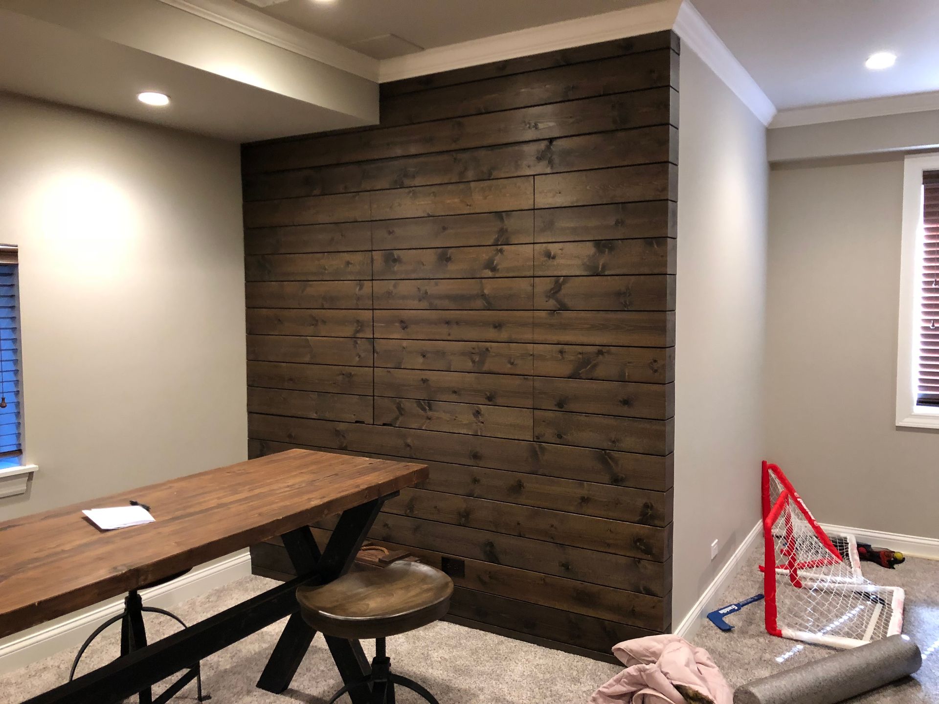 A room with a wooden wall and a wooden table and chairs.