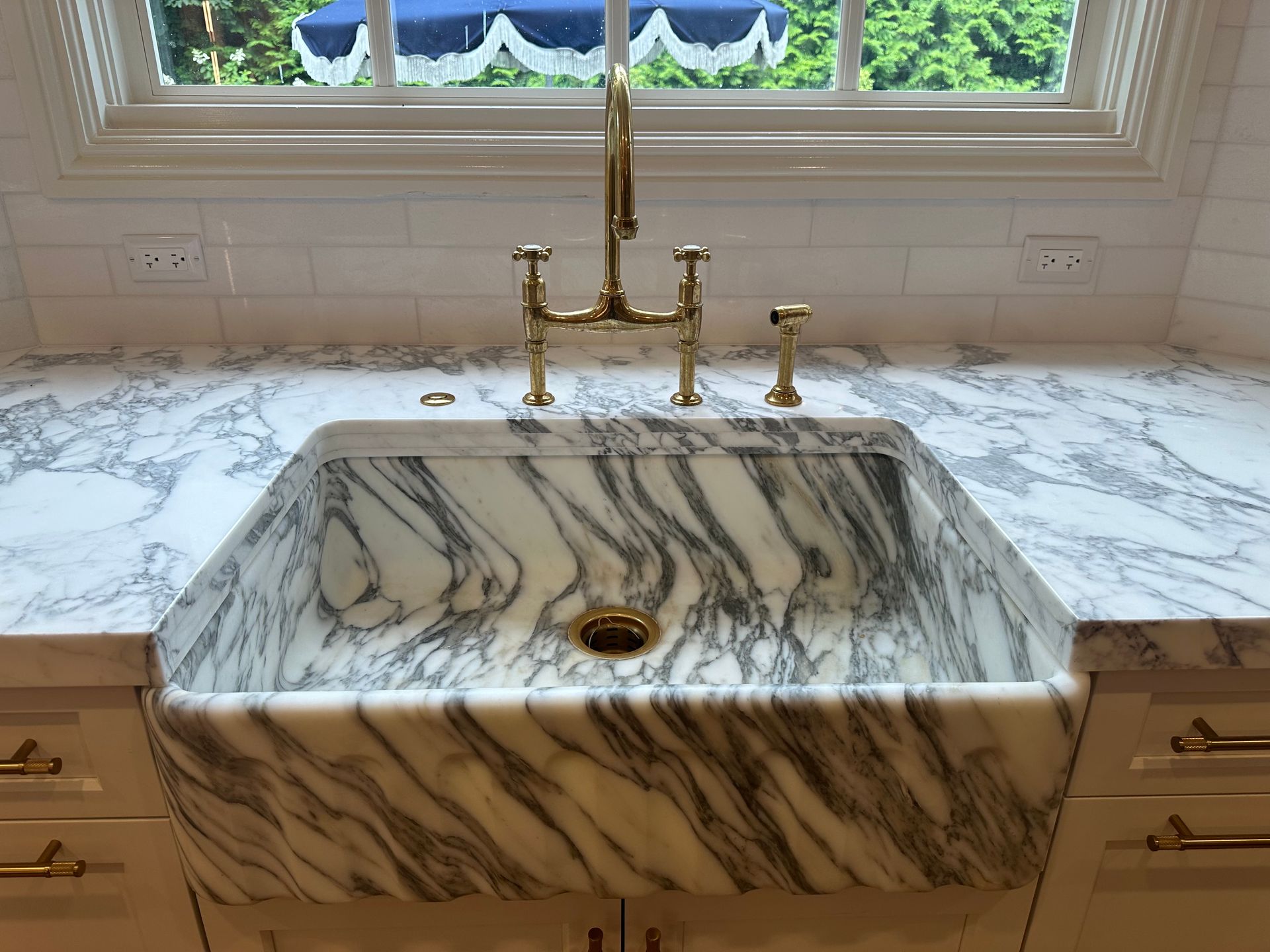 A kitchen sink with a marble counter top and a faucet