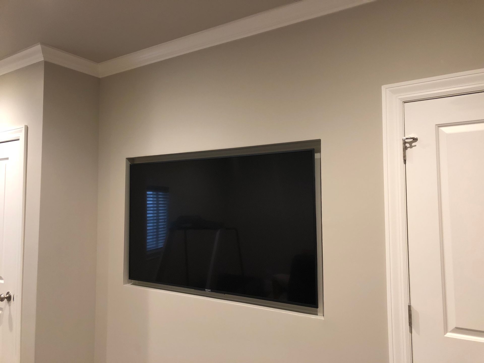 A flat screen tv is mounted in a hole in the wall.