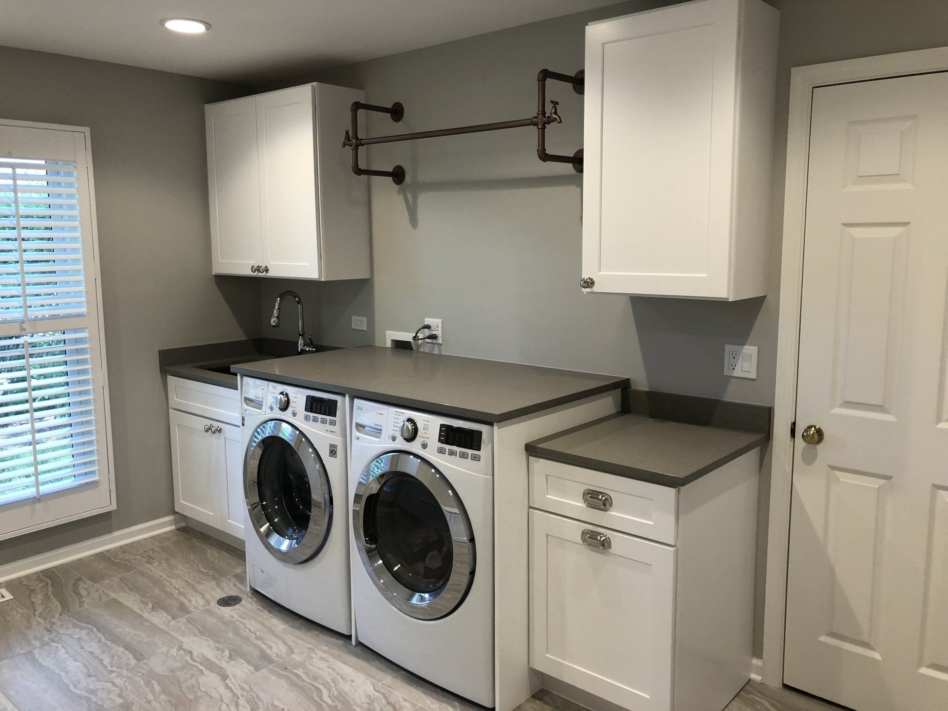 A laundry room with a washer and dryer and white cabinets.