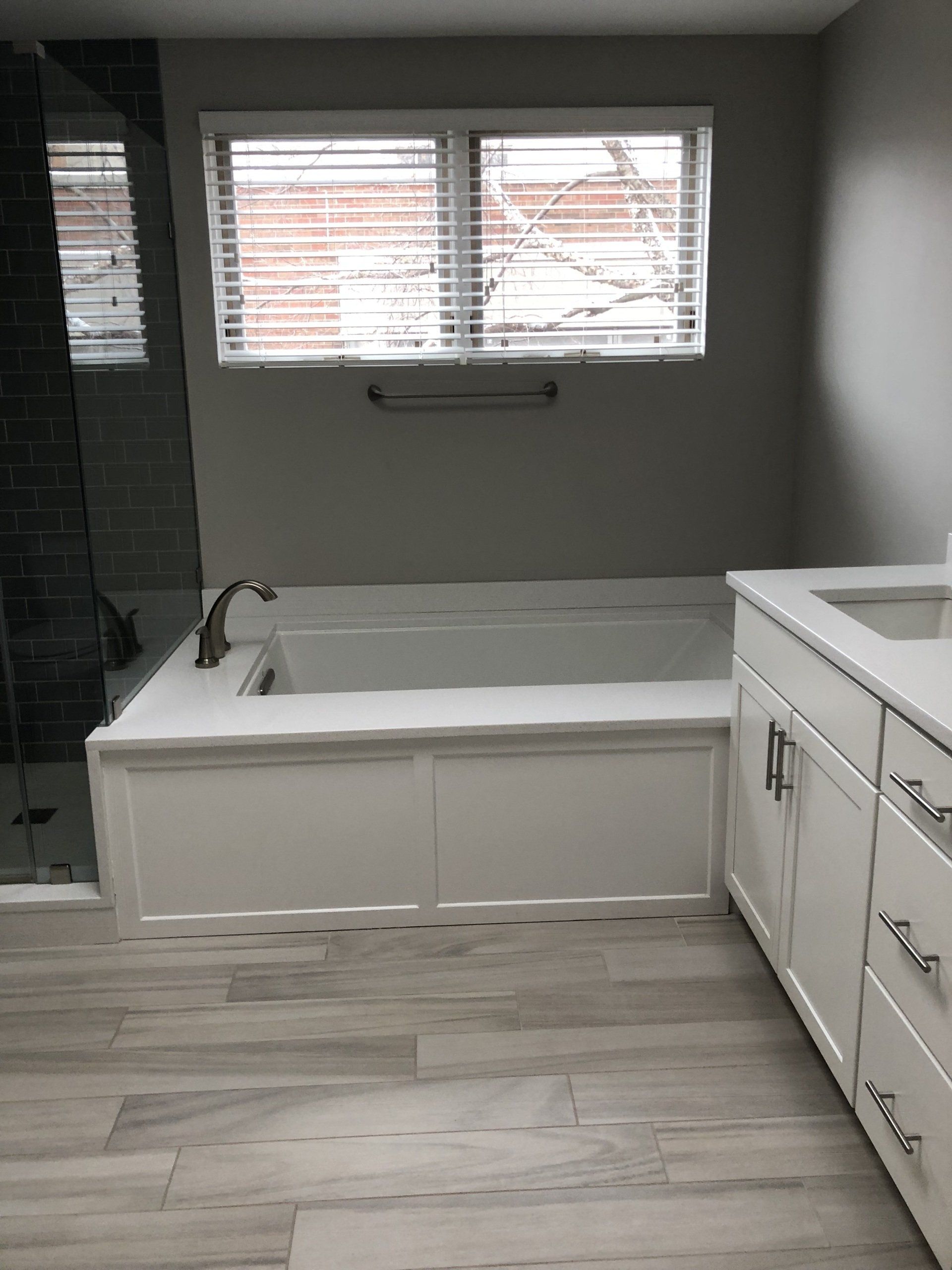 A bathroom with a tub , sink , and window.