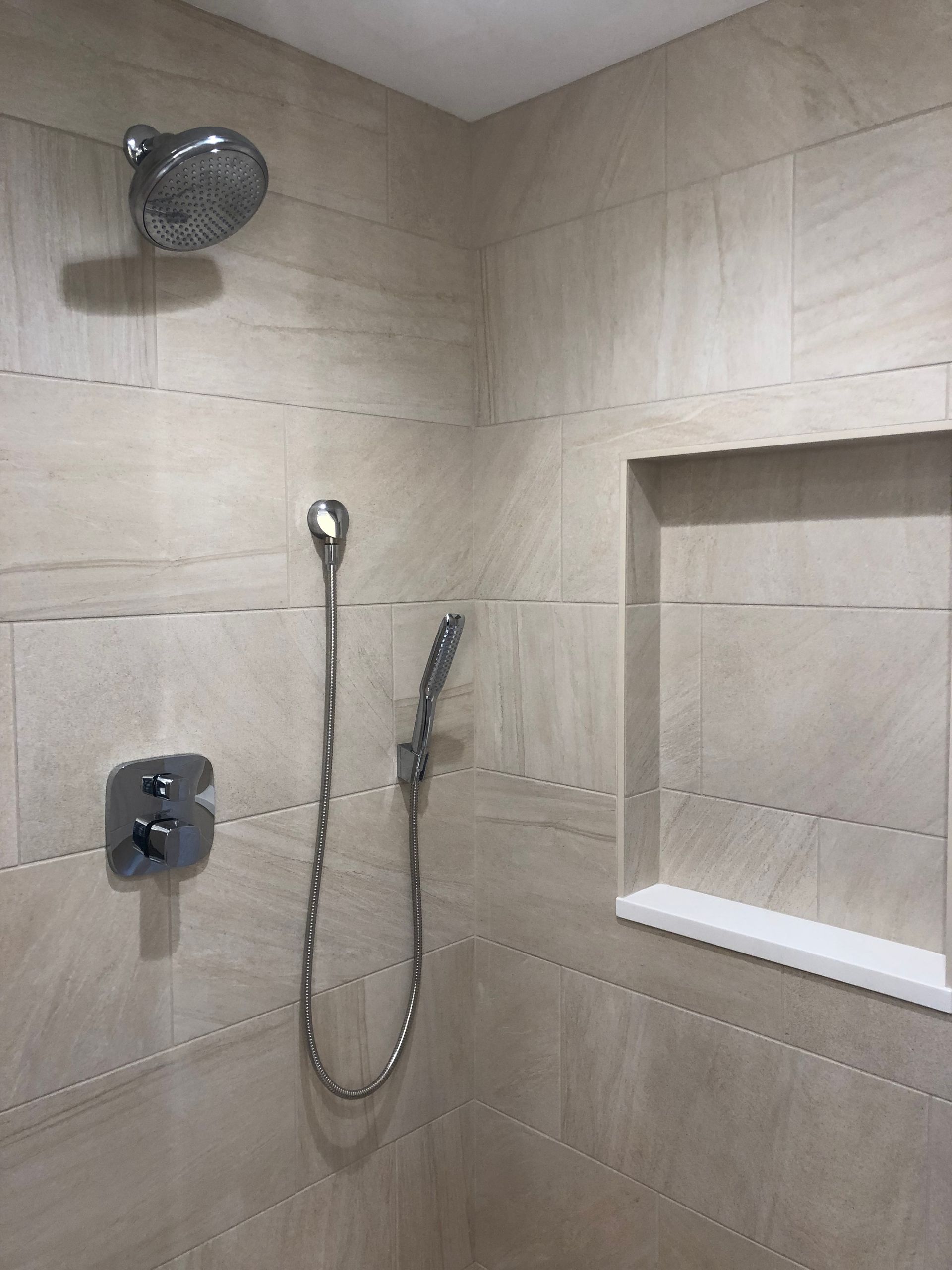 A shower with a shower head and a hose attached to it.