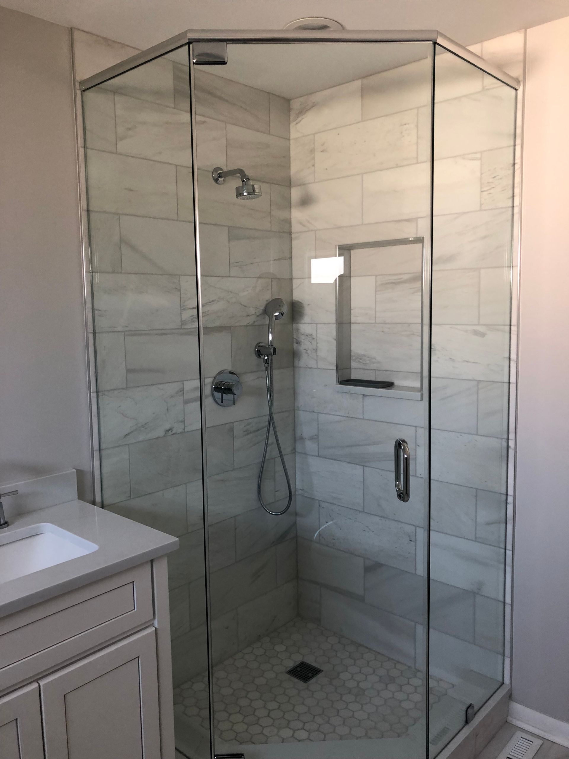 A bathroom with a glass shower door and a sink.