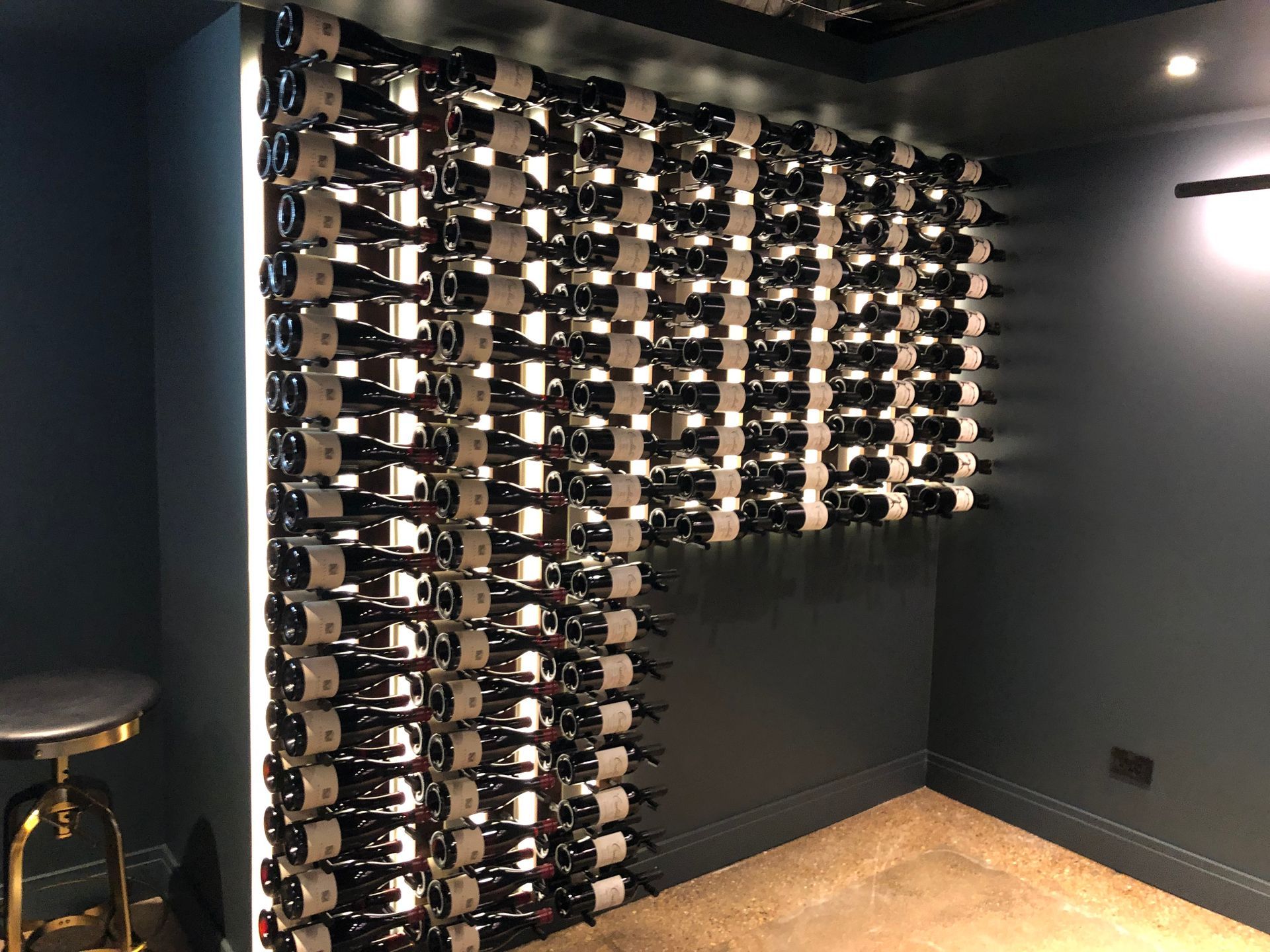 A room with a lot of wine bottles on the wall.