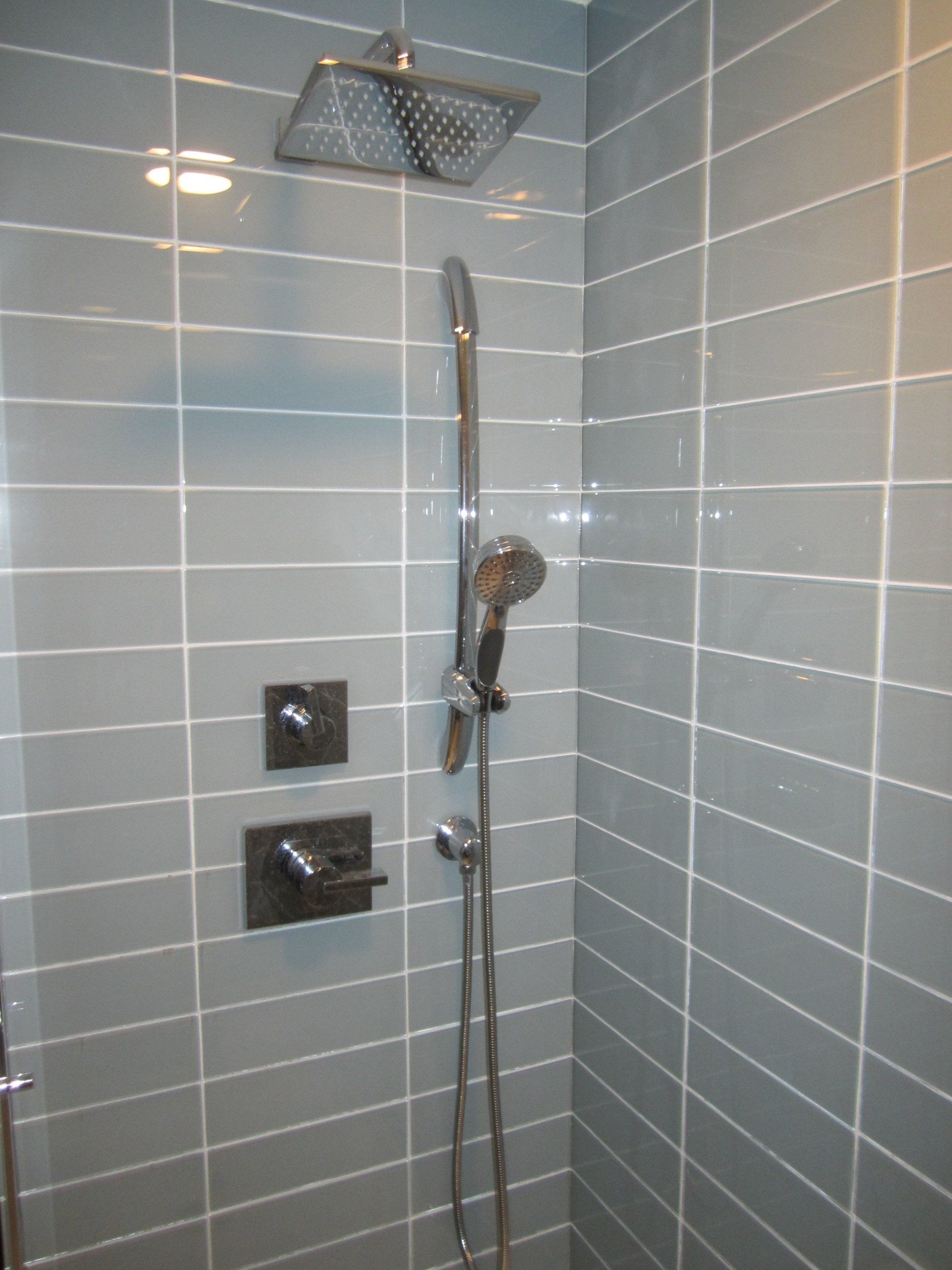 A shower with blue tiles and a shower head