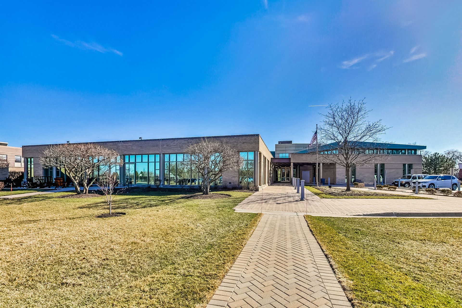 A large building with a lot of windows is surrounded by grass and trees.