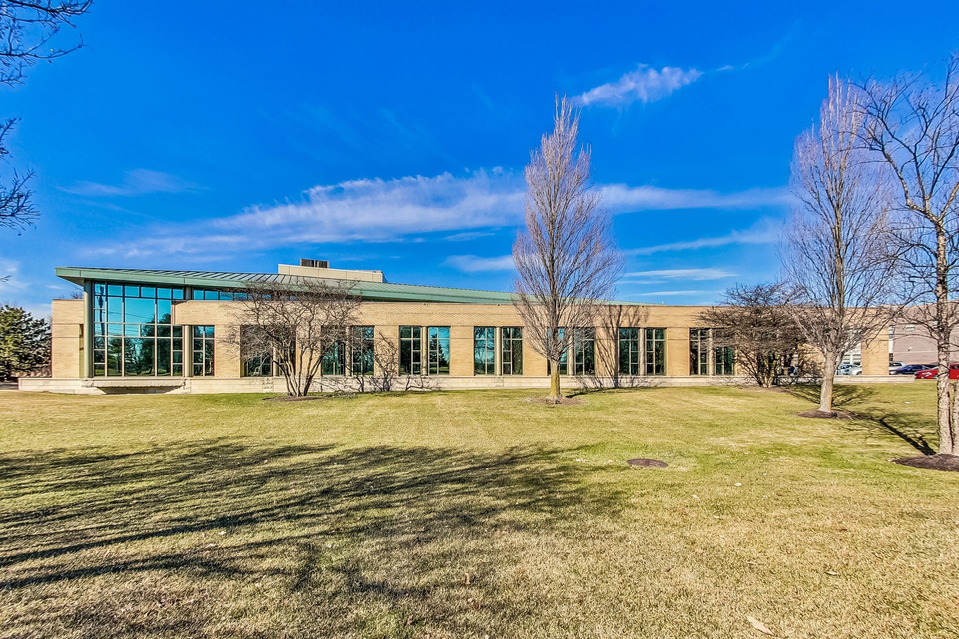 A large building with a lot of windows is sitting in the middle of a grassy field.