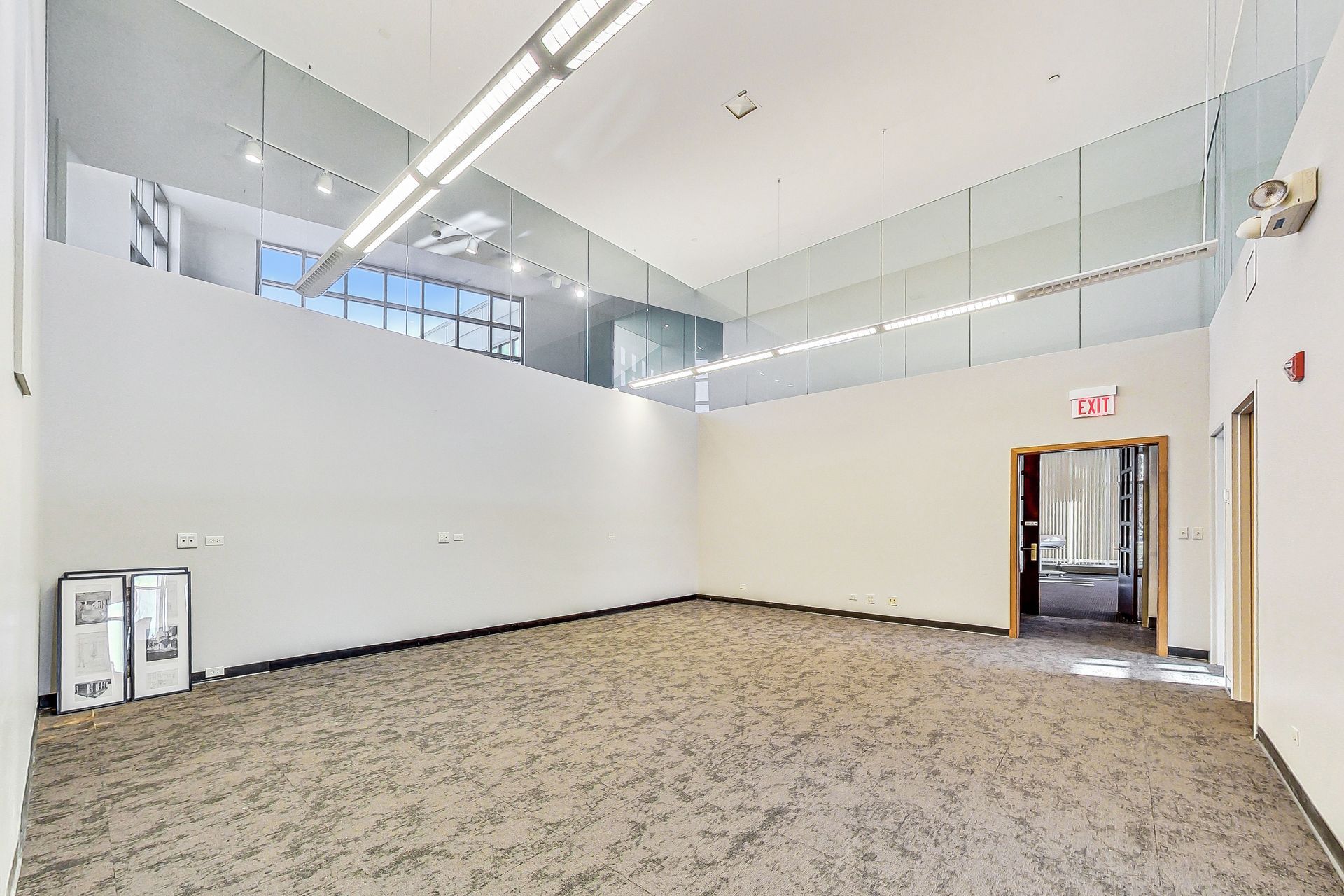 An empty room with a carpeted floor and a large window.