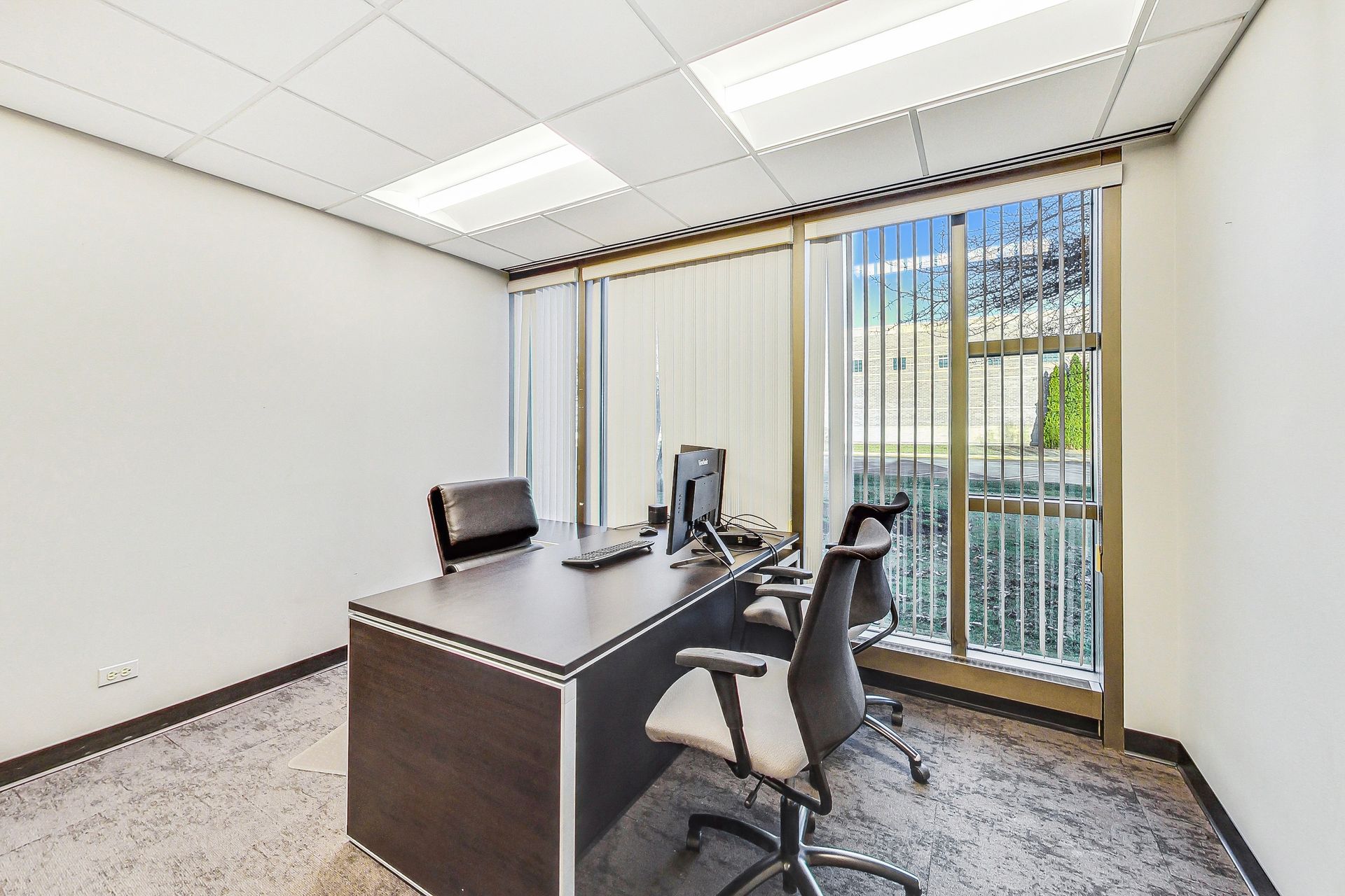 A small office with a desk and chairs and a window
