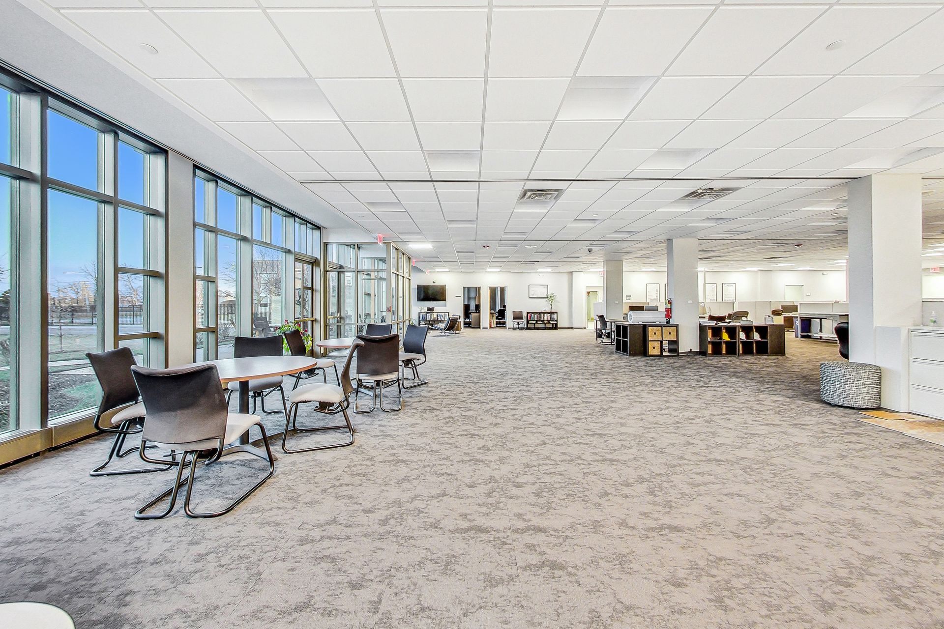 A large room with tables and chairs in it and a lot of windows.