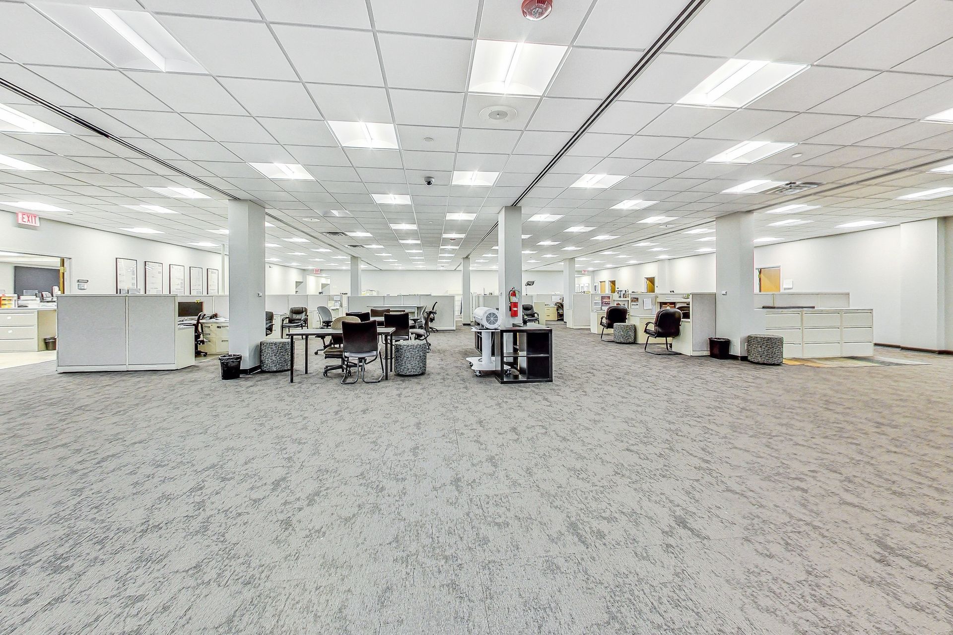 A large empty office with a lot of desks and chairs.