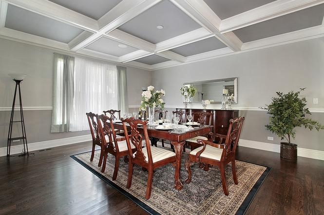 A dining room with a table and chairs and a rug on the floor.