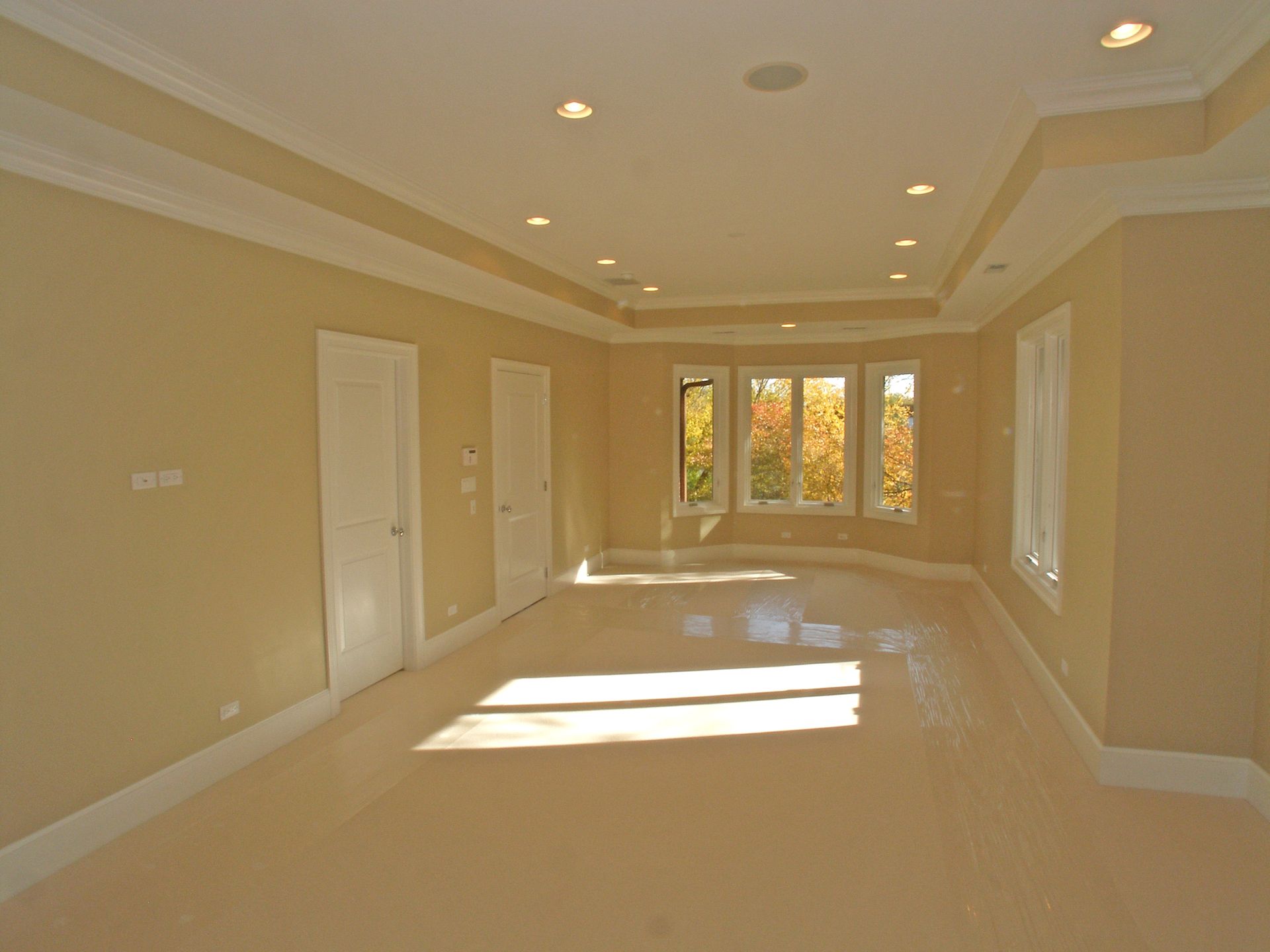A large empty room with tan walls and white trim