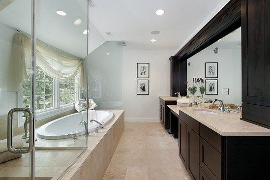 A bathroom with two sinks , a tub , and a large mirror.