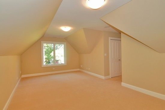 An empty room with a slanted ceiling and a window