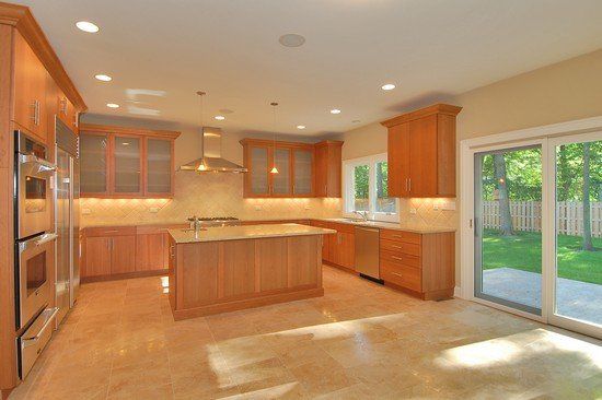 An empty kitchen with wooden cabinets and stainless steel appliances
