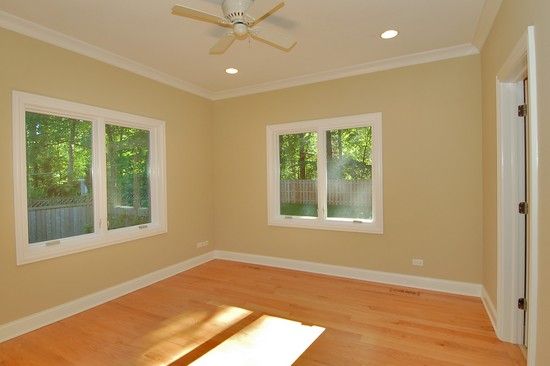 An empty room with three windows and a ceiling fan