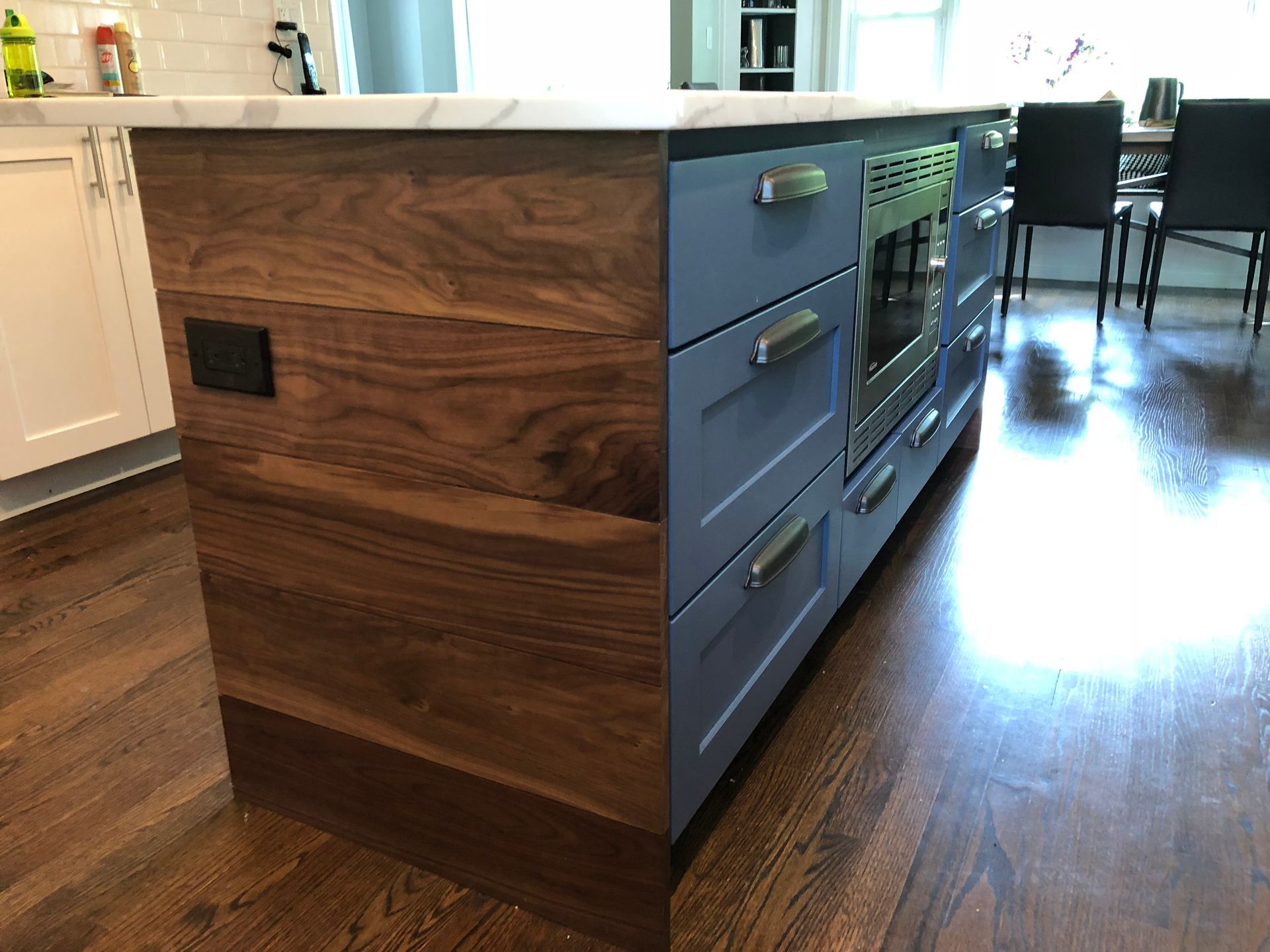 A kitchen island with wooden drawers and a marble counter top.
