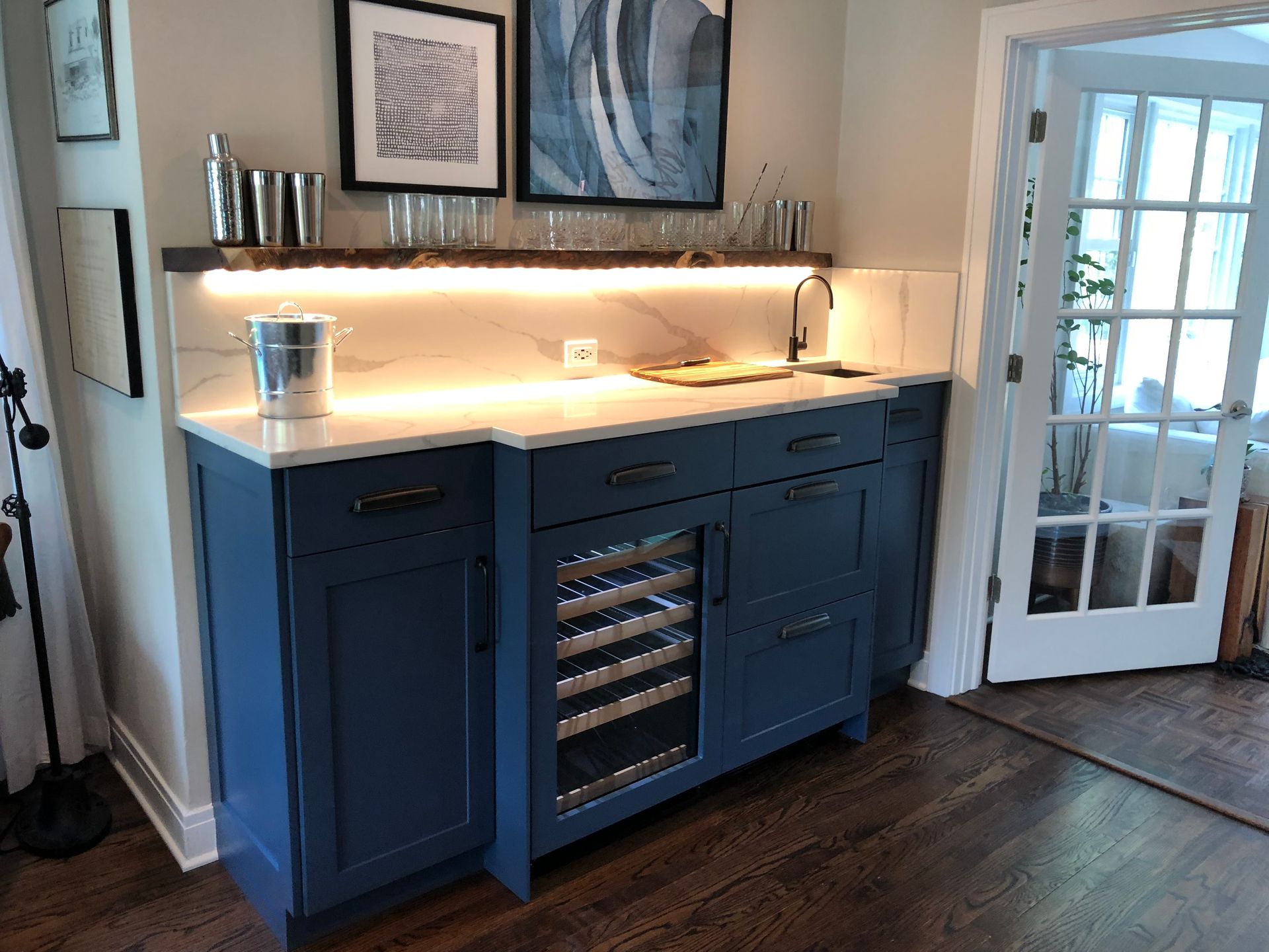 A kitchen with blue cabinets and a wine cooler.
