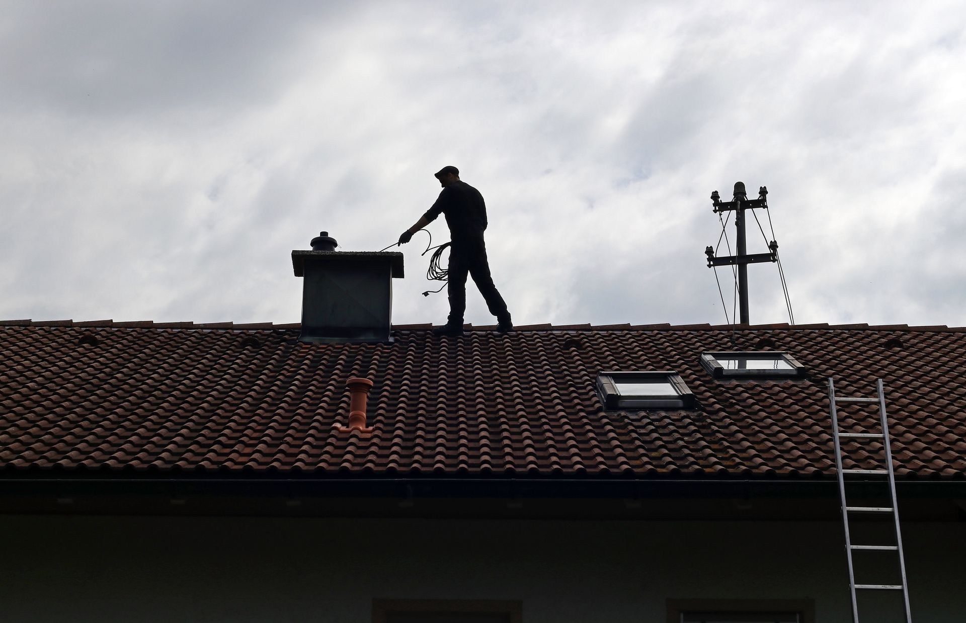 A Man Standing on Top of A Roof with A Ladder