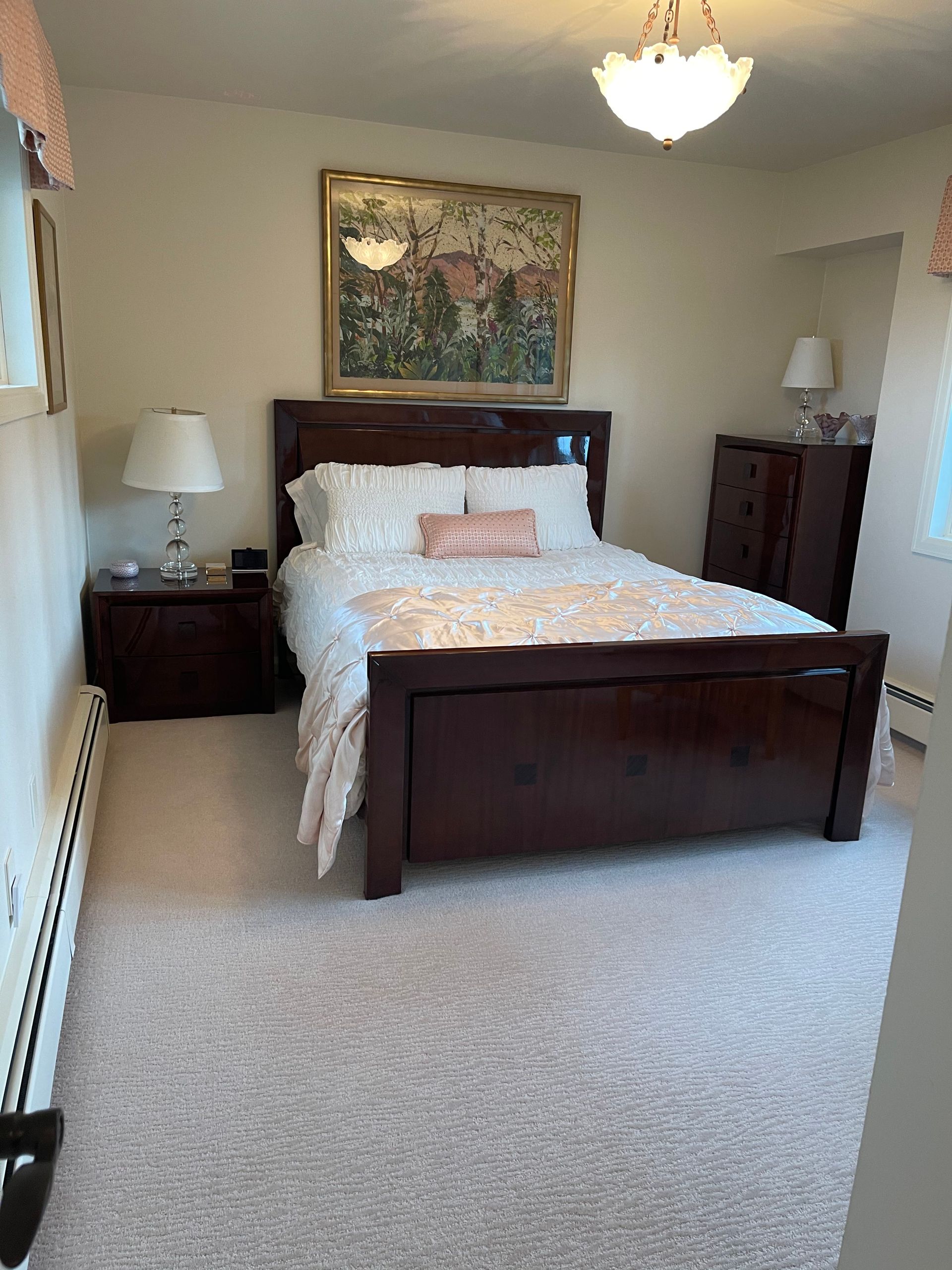 A bedroom with a bed , nightstands , and a picture on the wall.