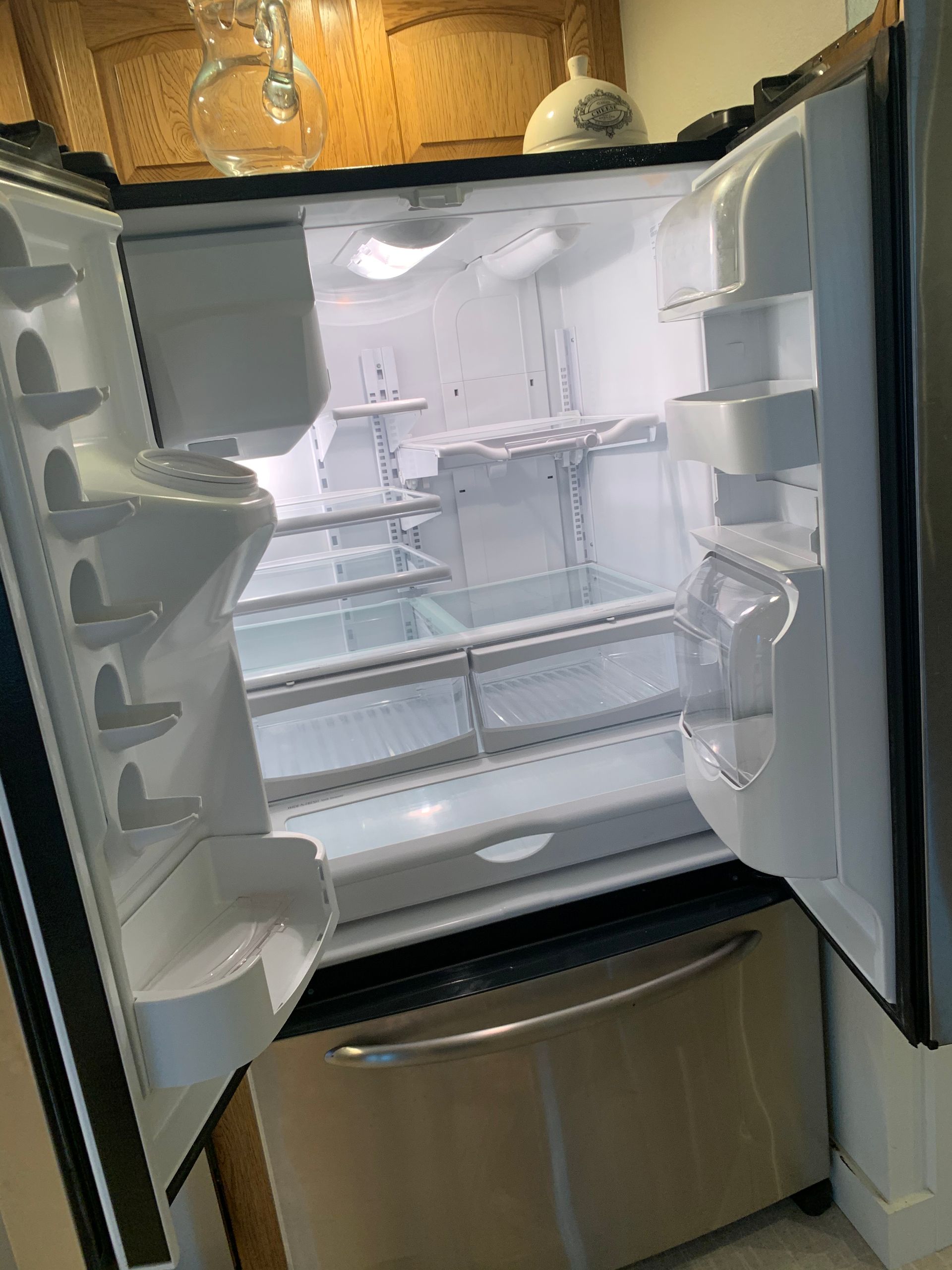An empty refrigerator with the door open in a kitchen.