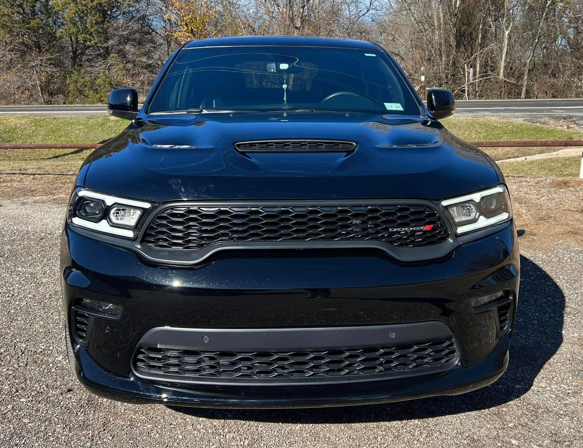 A black Dodge Durango SUV parked outdoors, seen from the front, showcasing its grille, headlights, and hood scoop.