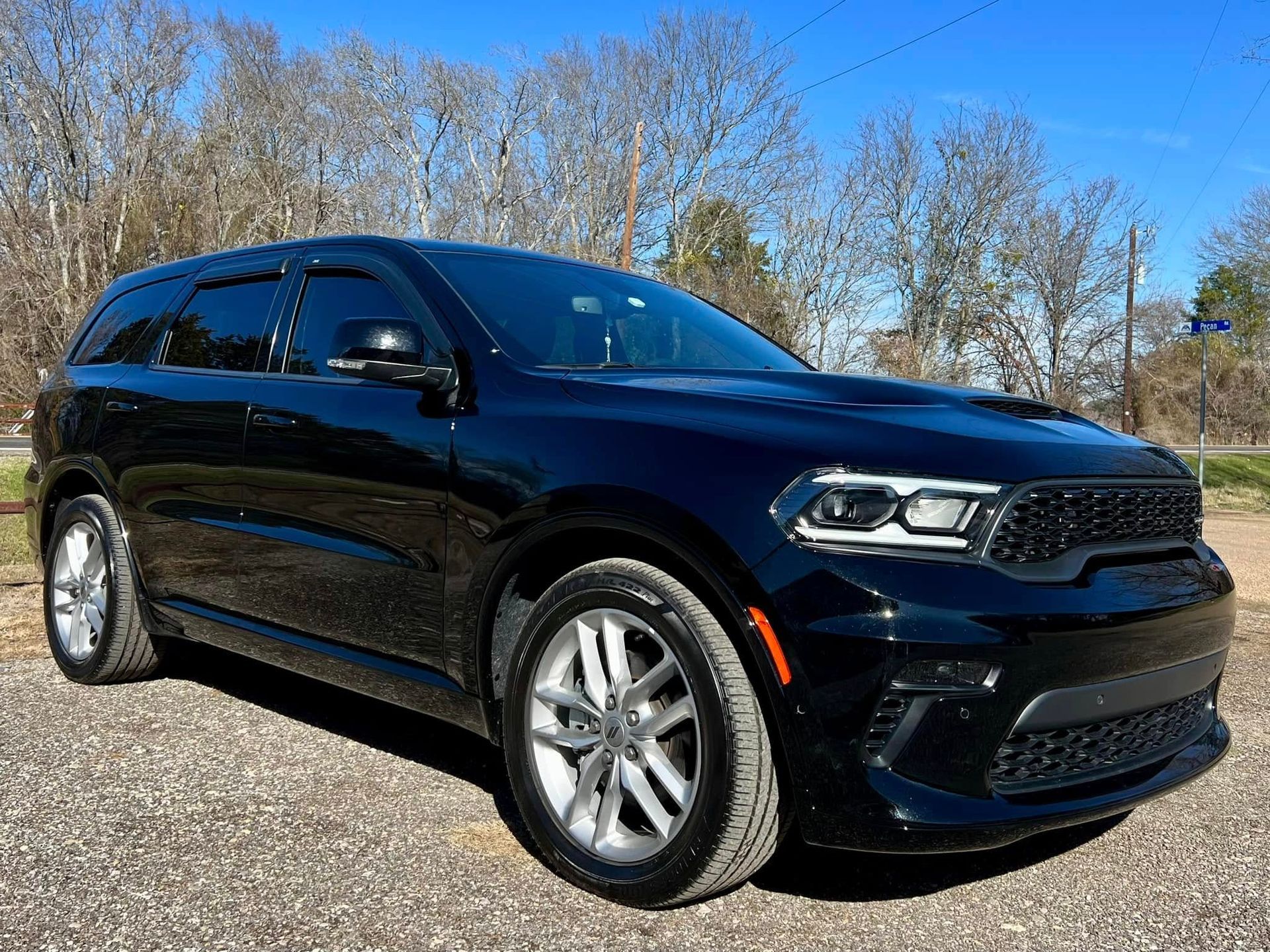 A black Dodge Durango SUV parked on a gravel surface under a clear blue sky.