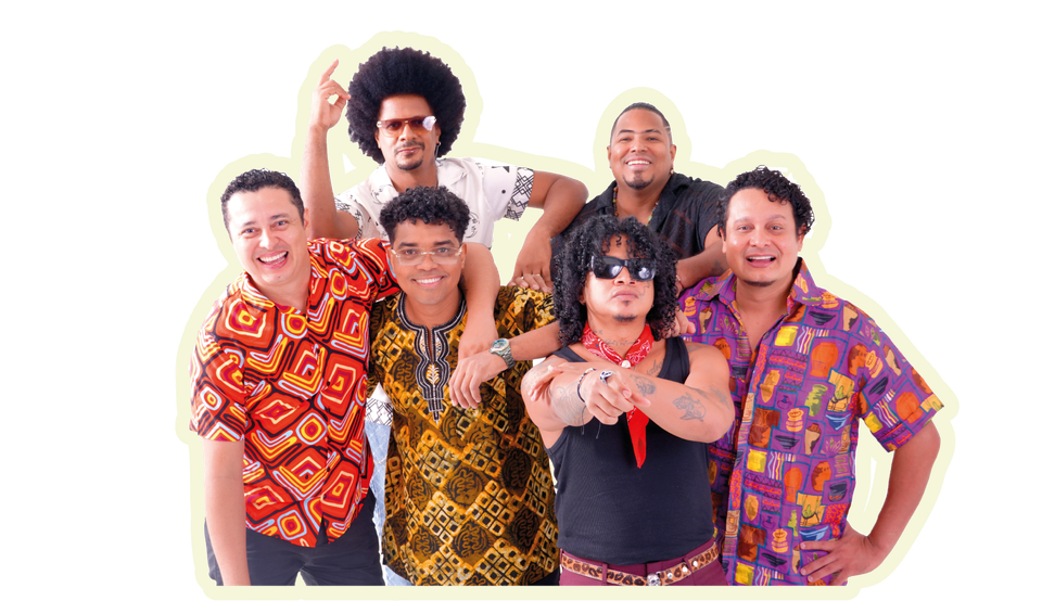 Seis músicos con camisetas coloridas posando juntos, algunos con afro, gafas de sol y señalando.