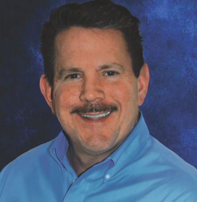 a man with a mustache is wearing a blue shirt and smiling .