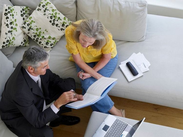 a man and woman are sitting on a couch looking at papers