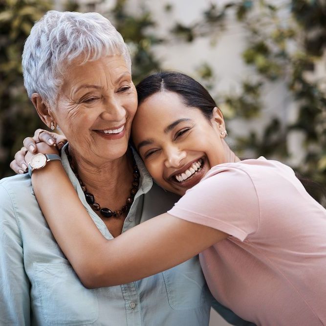 an older woman and a younger woman hugging and smiling