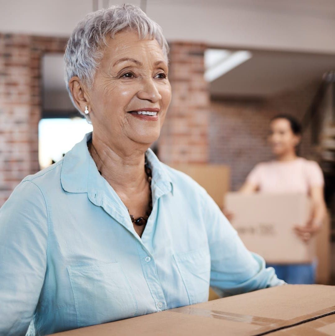 a woman in a blue shirt is smiling while holding a cardboard box