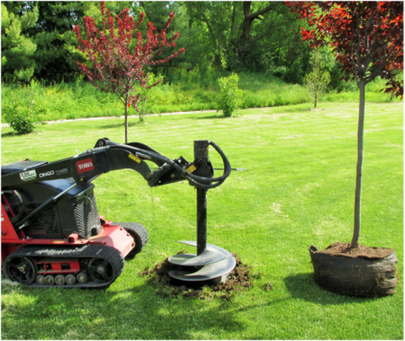 A tractor is digging a hole in the ground to plant a tree.