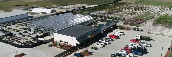 An aerial view of a greenhouse with a lot of cars parked in front of it.