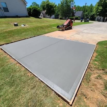 A concrete driveway with a lawn mower parked in the middle of it.