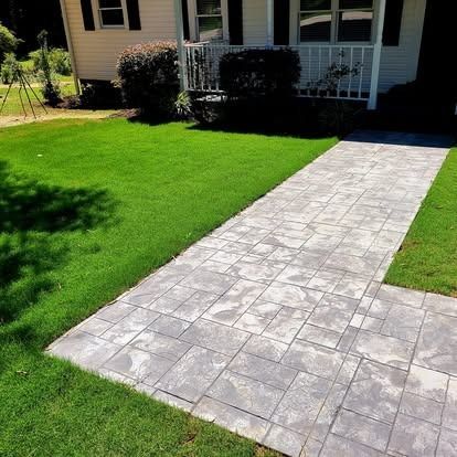 A walkway leading to a house with a lush green lawn.