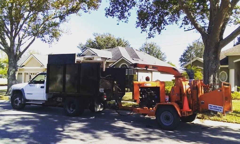 A truck with a tree chipper attached to it is parked in front of a house.