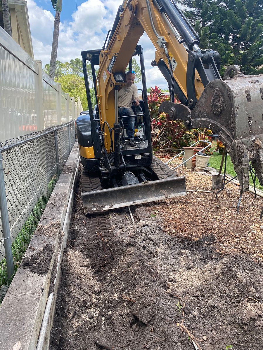 A yellow and black excavator is digging a hole in the ground.