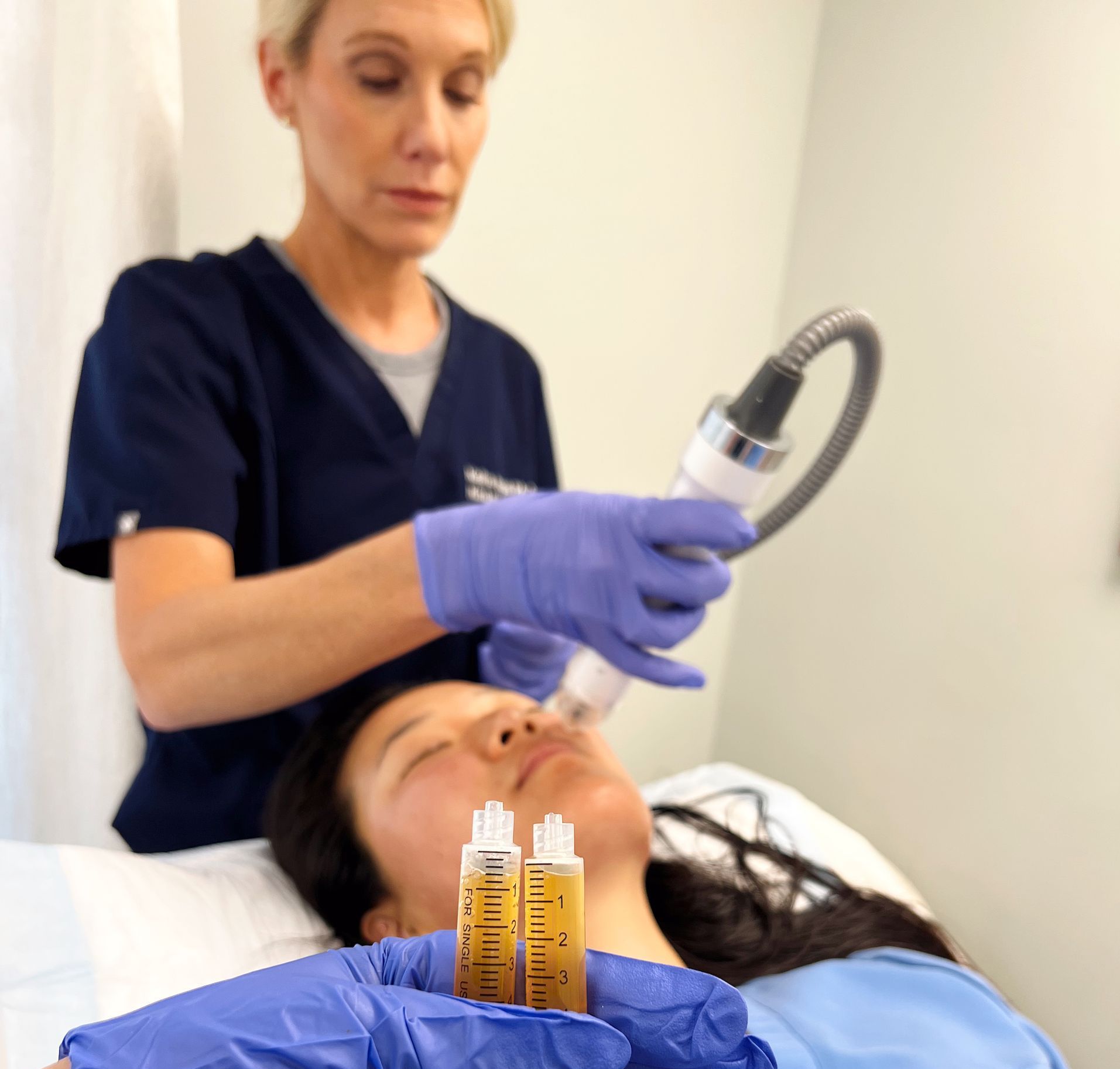A woman is getting a facial treatment from a nurse
